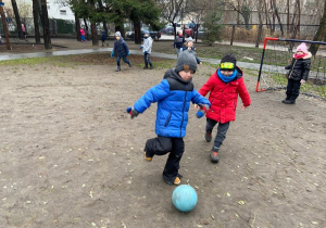 Dwóch chłopców biegnie za niebiesk piłką
